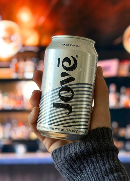 A hand holding up a can of Jovē Water